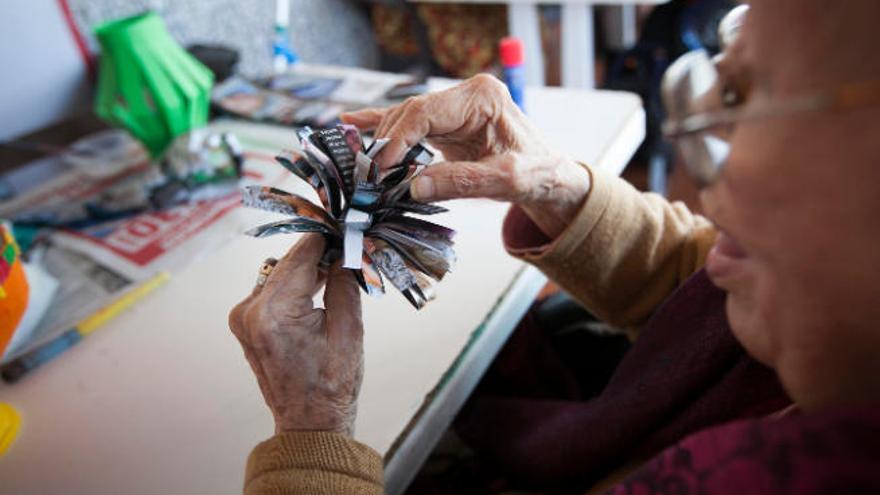 Una mujer mayor realiza manualidades en una residencia.