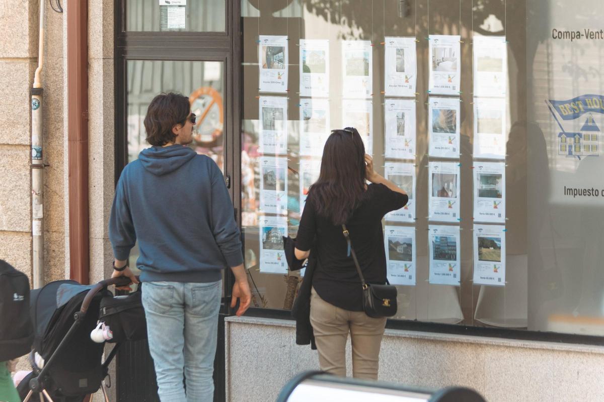 Una pareja ojea el escaparate de una inmobiliaria en Santiago.