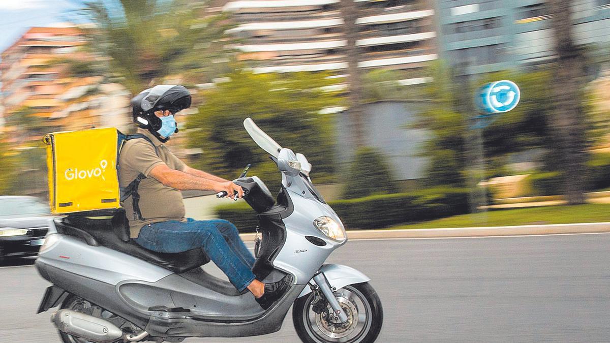 Un repartidor cruza en moto frente a la plaza de los Luceros de Alicante.