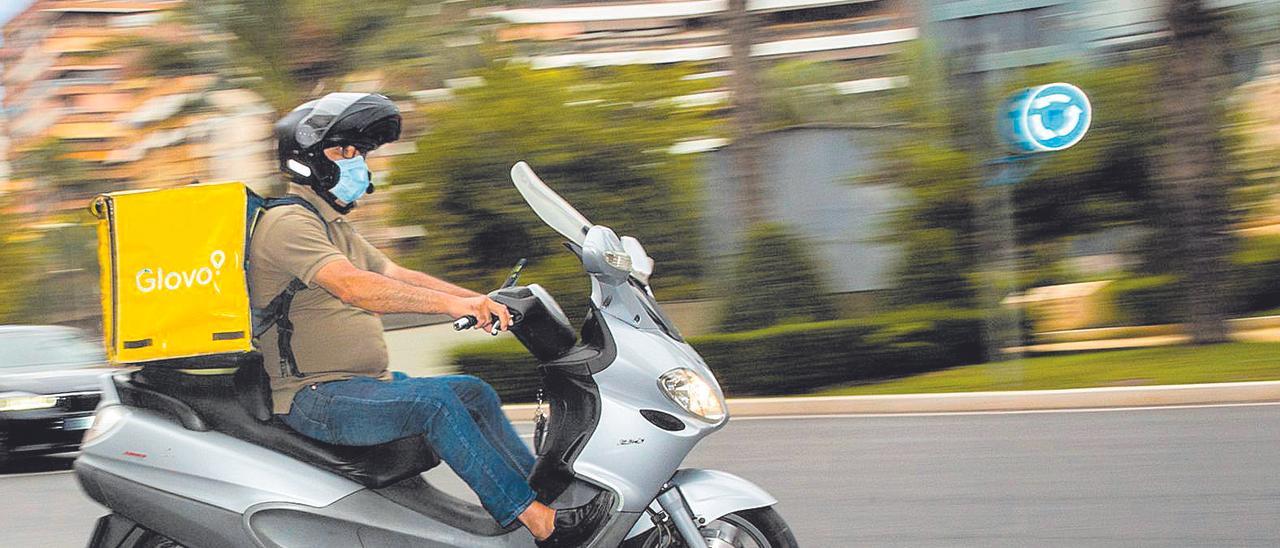 Un repartidor cruza en moto frente a la plaza de los Luceros de Alicante.