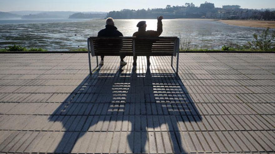 Dos hombres al sol en un banco en Sada.