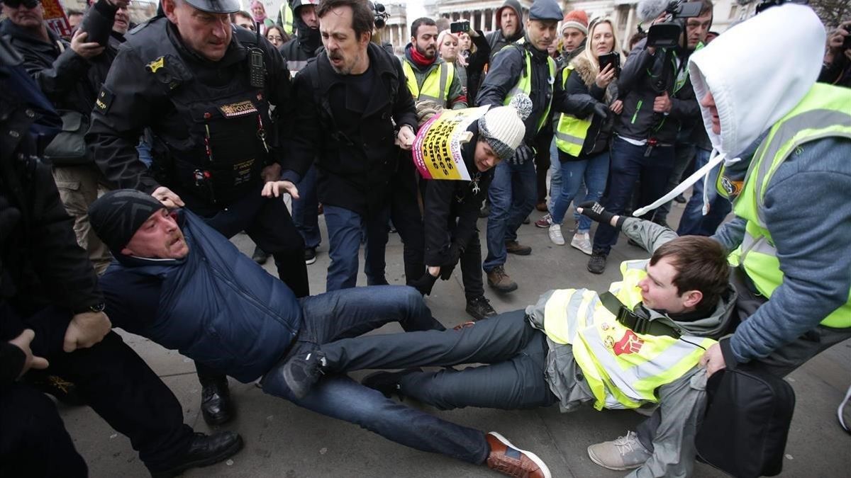 La policía británica y otros manifestantes separan a un partidario y un detractor del 'brexit' en una marcha en Londres.