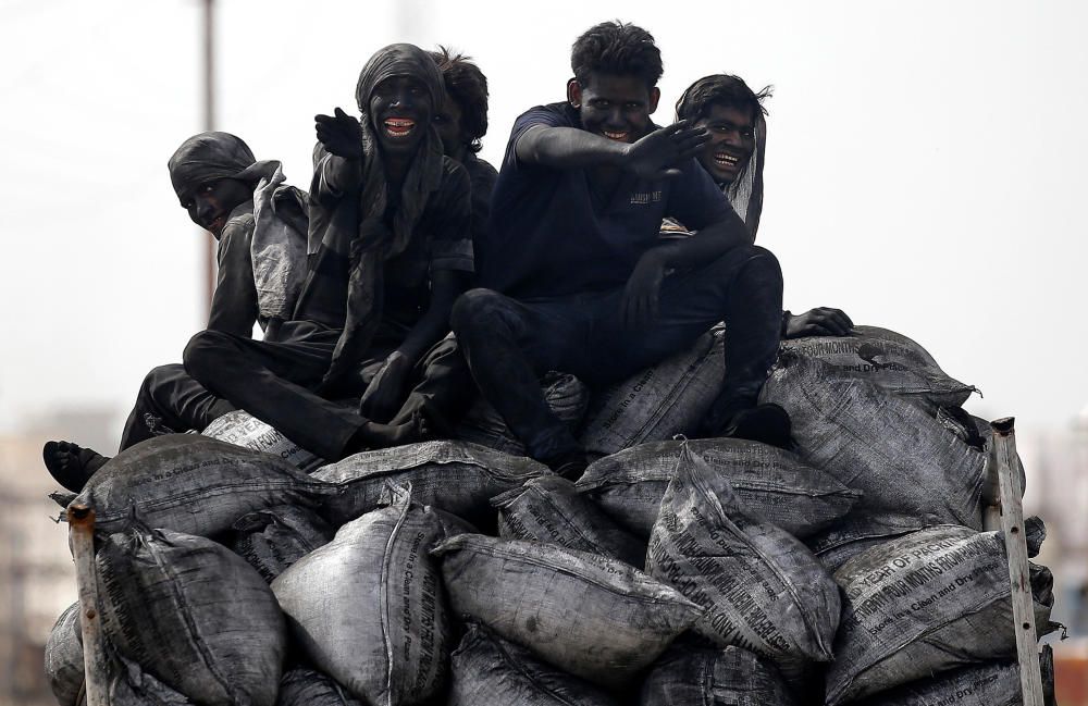 Coal workers travel on the back of their lorry ...