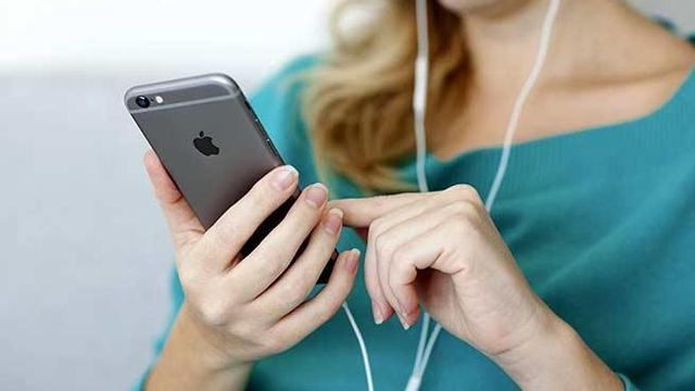 Una mujer usa los auriculares de un iPhone.