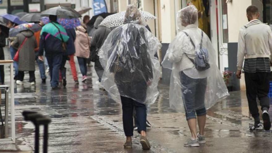 Un grupo de turistas soprendido por la lluvia, ayer en el centro de València.