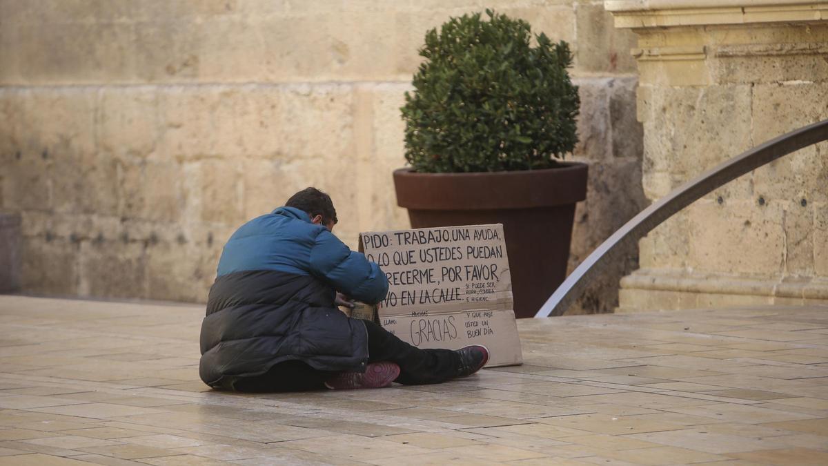 Una persona pide dinero y trabajo en una calle de Alicante