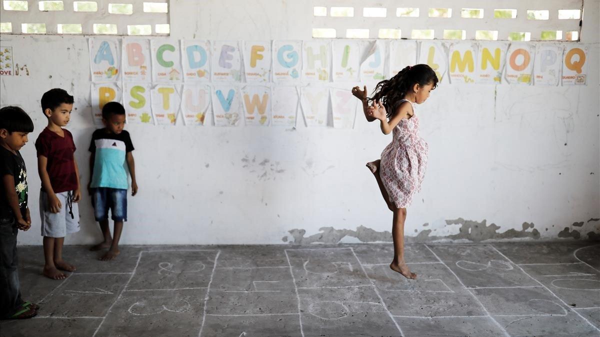 Los niños Adriel, Matheus, y Rian miran a su compañera de clase Michelly jugar en clase, en la escuela de Sao Jose en Morro de Belagua, Brasil.
