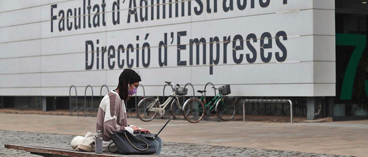 Una joven consulta su portátil, a las puertas de una facultad en el campus de Vera de la UPV.