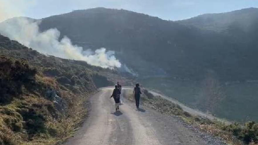 Senderistas, con el humo del incendio al fondo.