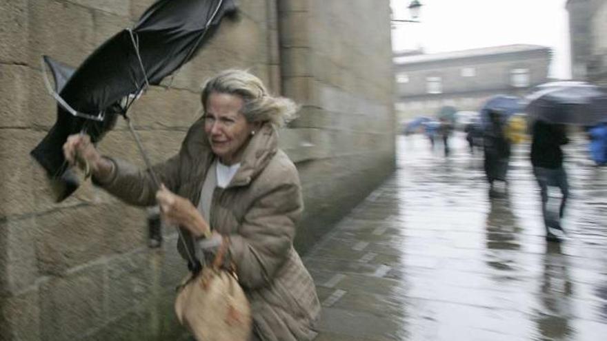 Una mujer camina con dificultad debido al viento en el casco antiguo de Santiago. / tucho valdés
