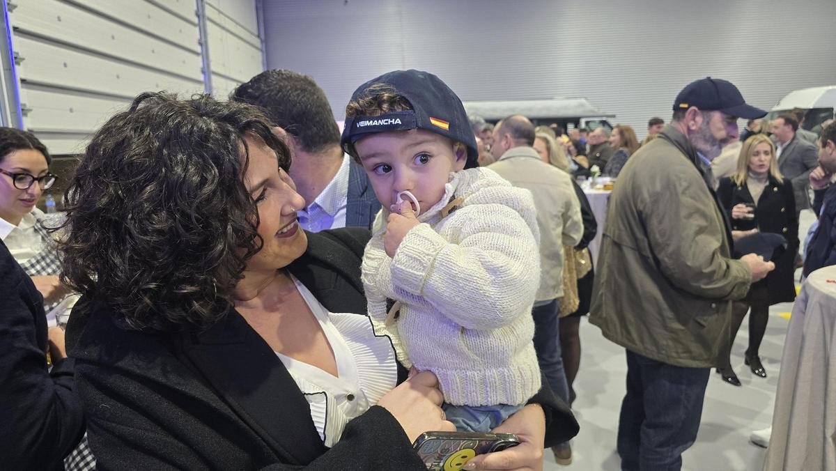 Una madre coge en brazos a su hija con una gorra del evento.