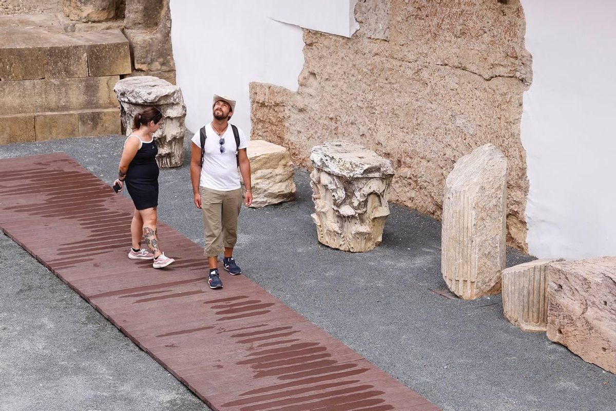 Una pareja de turistas visitan el Templo Romano de Córdoba.