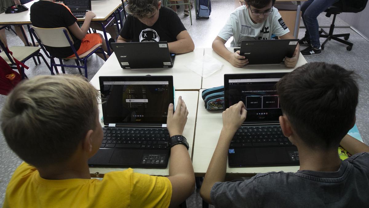 Varios alumnos en un CEIP de valencia utilizando un ordenador portátil.