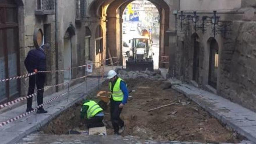 Un vianant observa les obres, amb el portal del Pont al fons