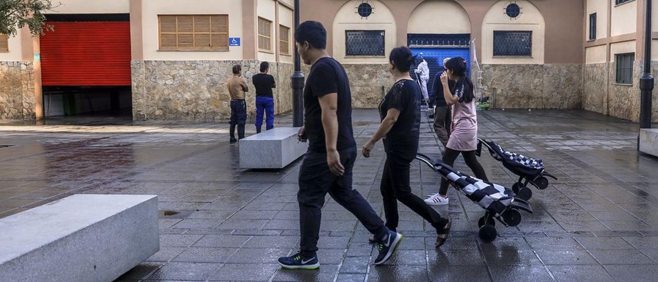 Varias personas pasan frente a un mercado de Palma.