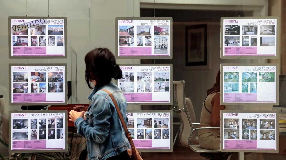Una joven pasa junto a las ofertas de viviendas de una inmobiliaria.