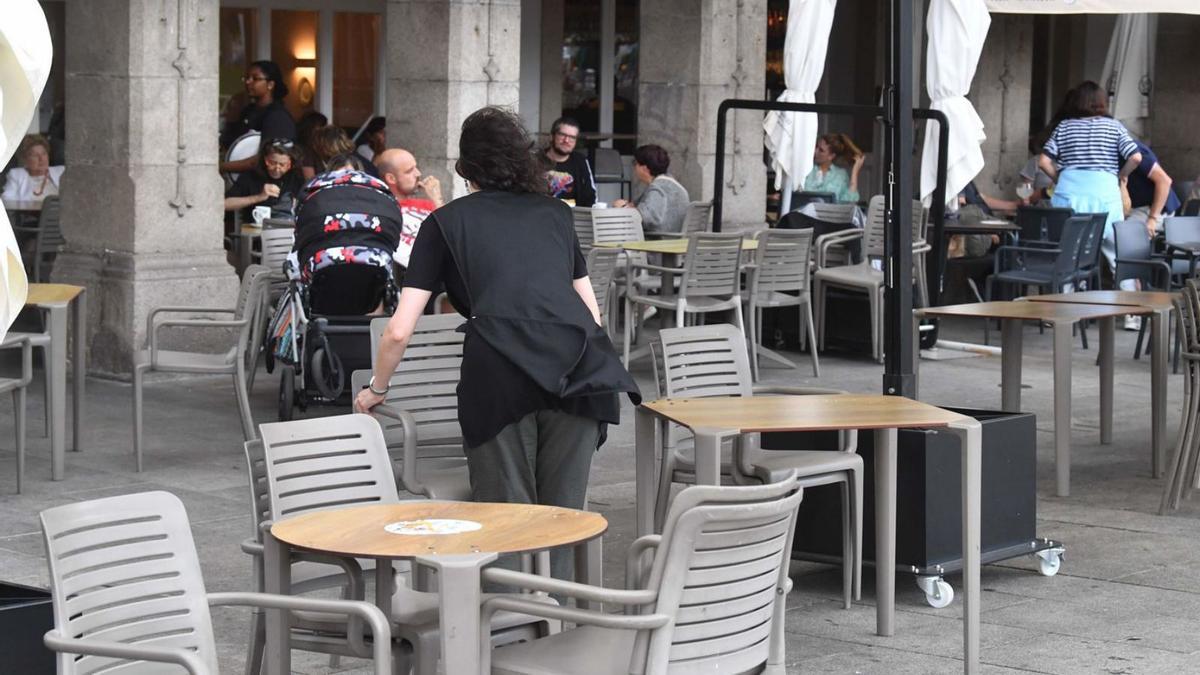 Una camarera instala una terraza en la Marina. | // VÍCTOR ECHAVE