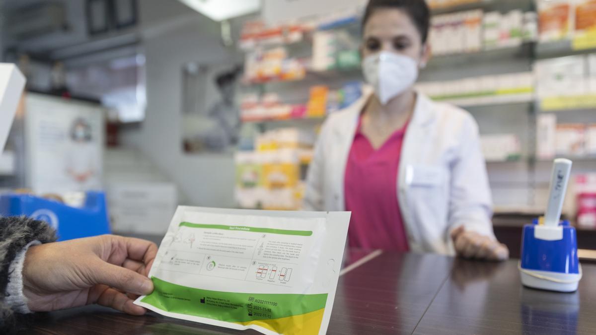 Una mujer con un test de antígenos en una farmacia.