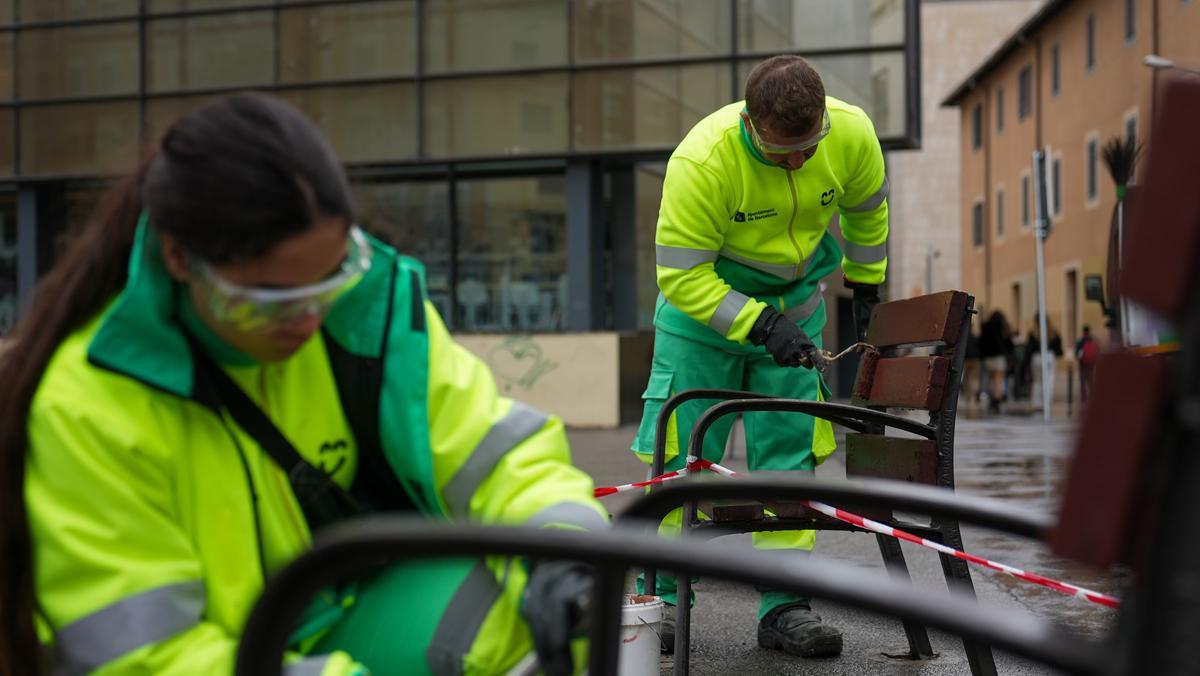 Efectivos de Cuidem Barcelona realizando tareas de limpieza de pintadas sobre bancos urbanos.