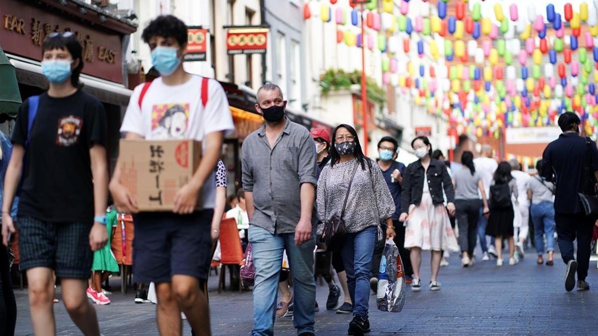 Ciudadanos con mascarilla caminan por el barrio chino de Londres, este domingo.