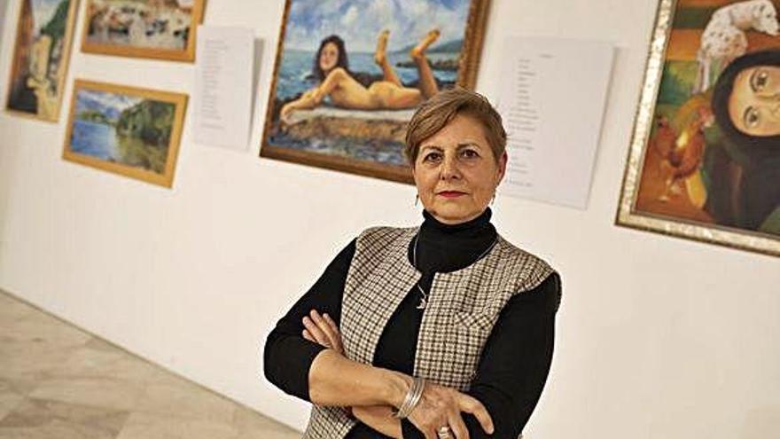 Arriba, la artista Charo Antón junto a varias de sus obras. A la izquierda, una mujer contempla uno de los paisajes expuestos en la Alhóndiga.