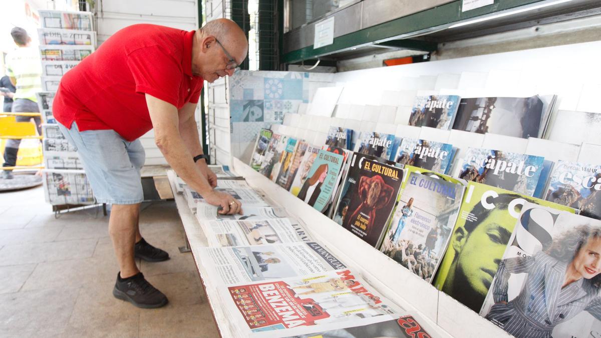 Isidro ordenando los periódicos en el frontal del kiosko de la Rambla