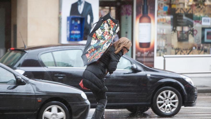 Una mujer intenta sujetar el paraguas, pese al viento.