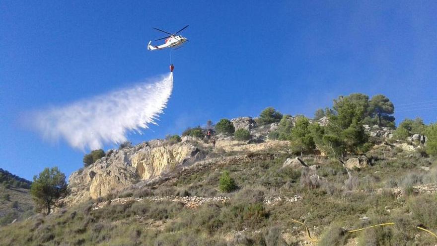 Un helicóptero descarga en la zona del incendio en Onil