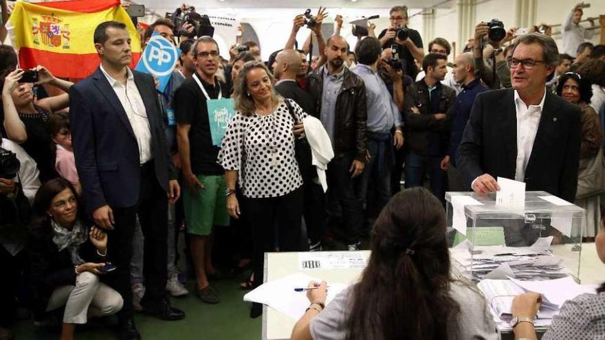 Artur Mas, votando, con simjpatizantes de PP y Vox agitando banderas y pancartas. // Reuters