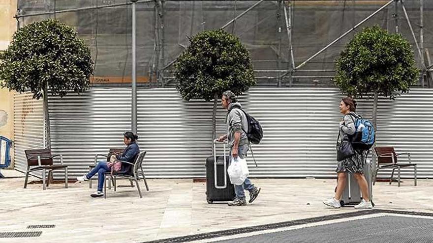 Una pareja de turistas pasea con sus maletas por el centro de Palma.