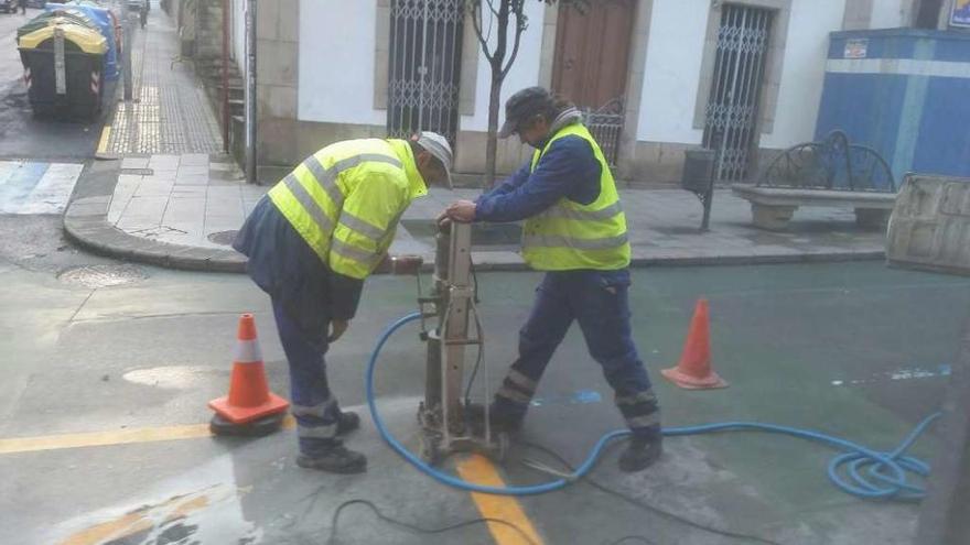 Dos operarios realizan obras para la colocación de una valla en el cruce entre Principal y Calvo Garra.