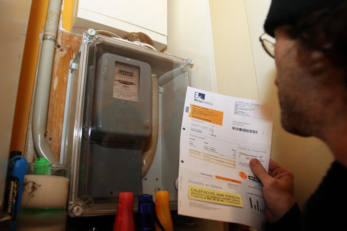 Un noi repassa la factura de la llum davant del comptador.
