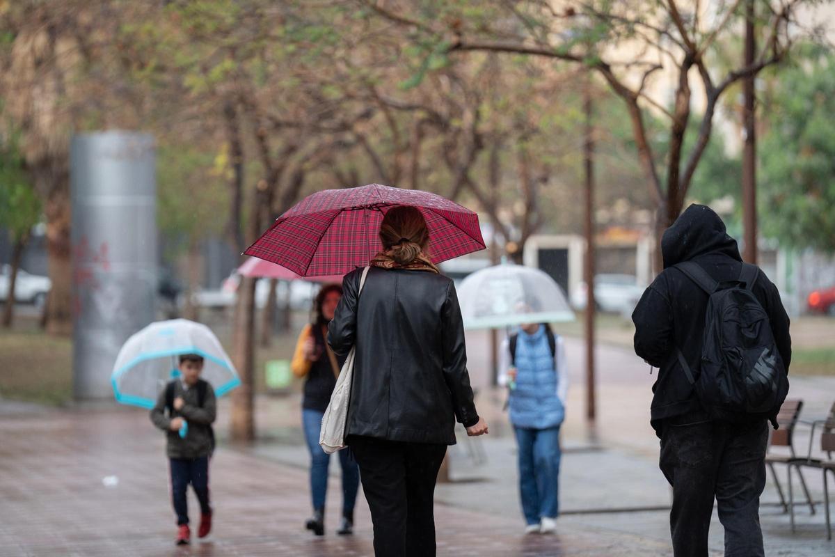Gent abrigada i amb el paraigua a la mà en un dia de fred i pluja en una imatge d'arxiu