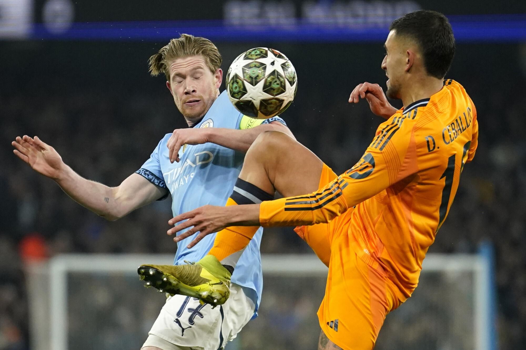 Real Madrid's Dani Ceballos, right, challenges Manchester City's Kevin De Bruyne during the Champions League playoff first leg soccer match between Manchester City and Real Madrid at the Etihad Stadium in Manchester, England, Tuesday, Feb. 11, 2025. (AP Photo/Dave Thompson)