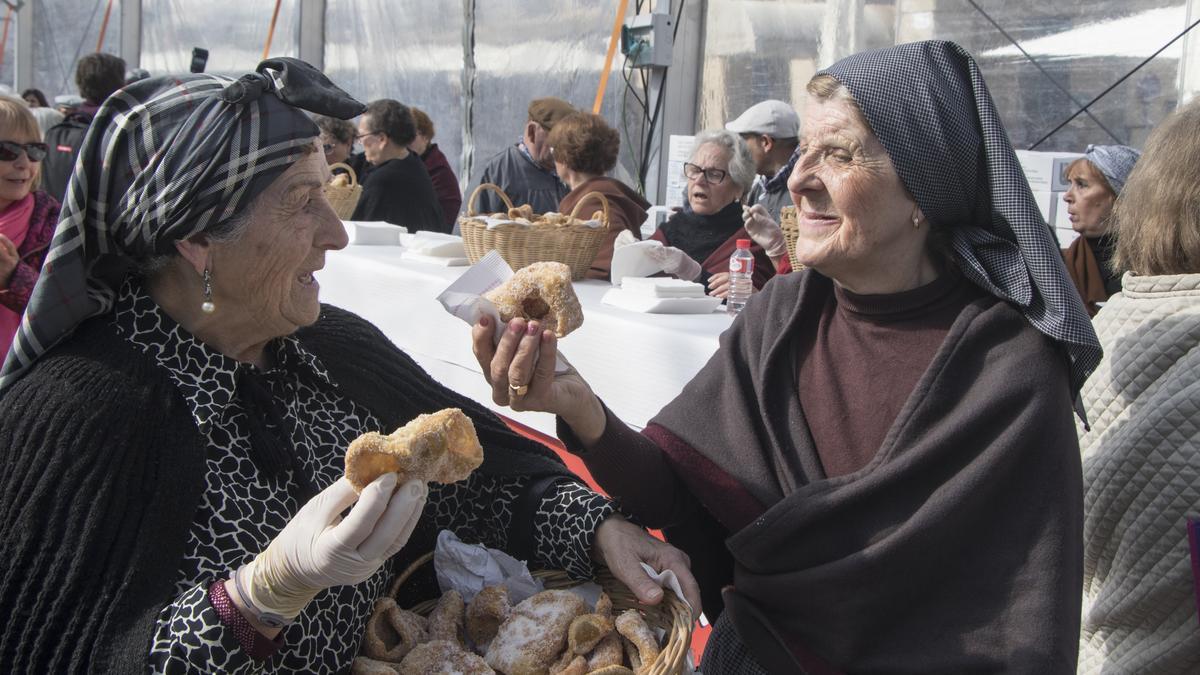 Dos mujeres ataviadas de lavanderas degustan un dulce típico en la fiesta de la quema del pelele.