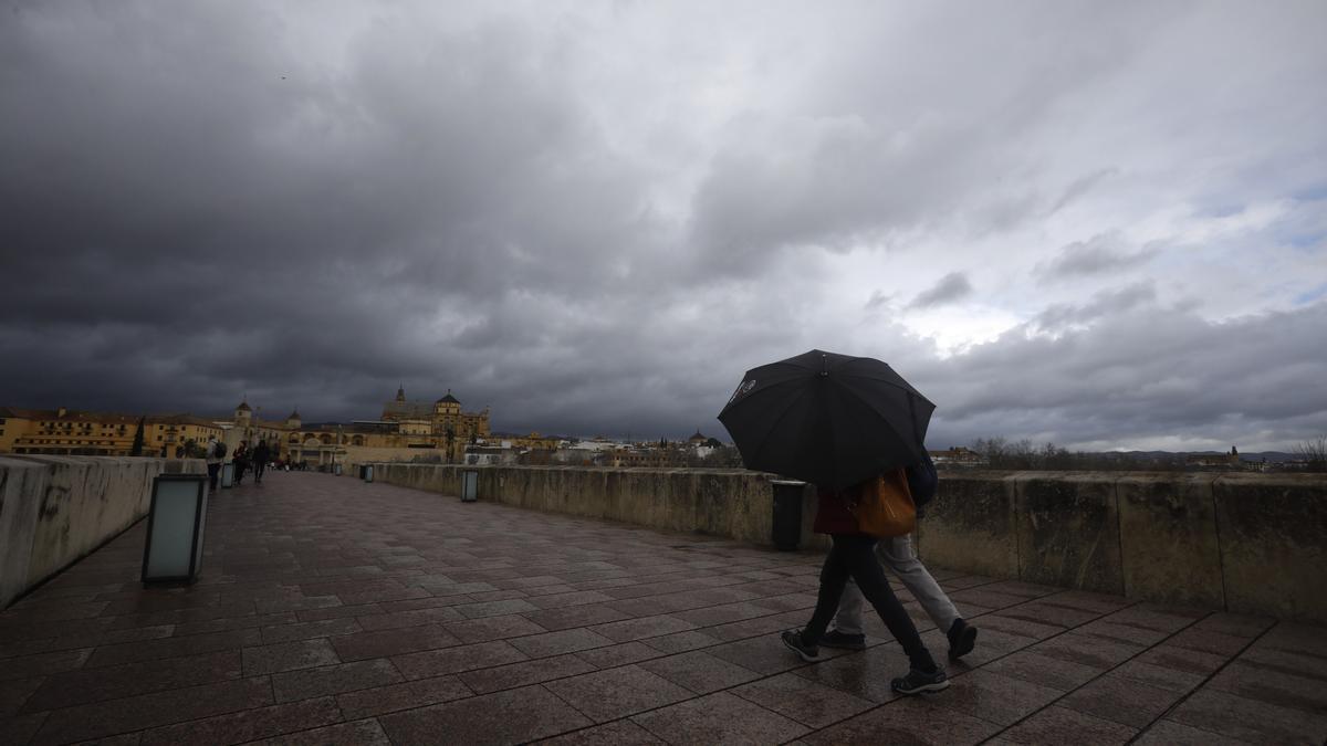 Dos personas se resguardan con un paragüas de la lluvia mientras caminan por el casco histórico de Córdoba.