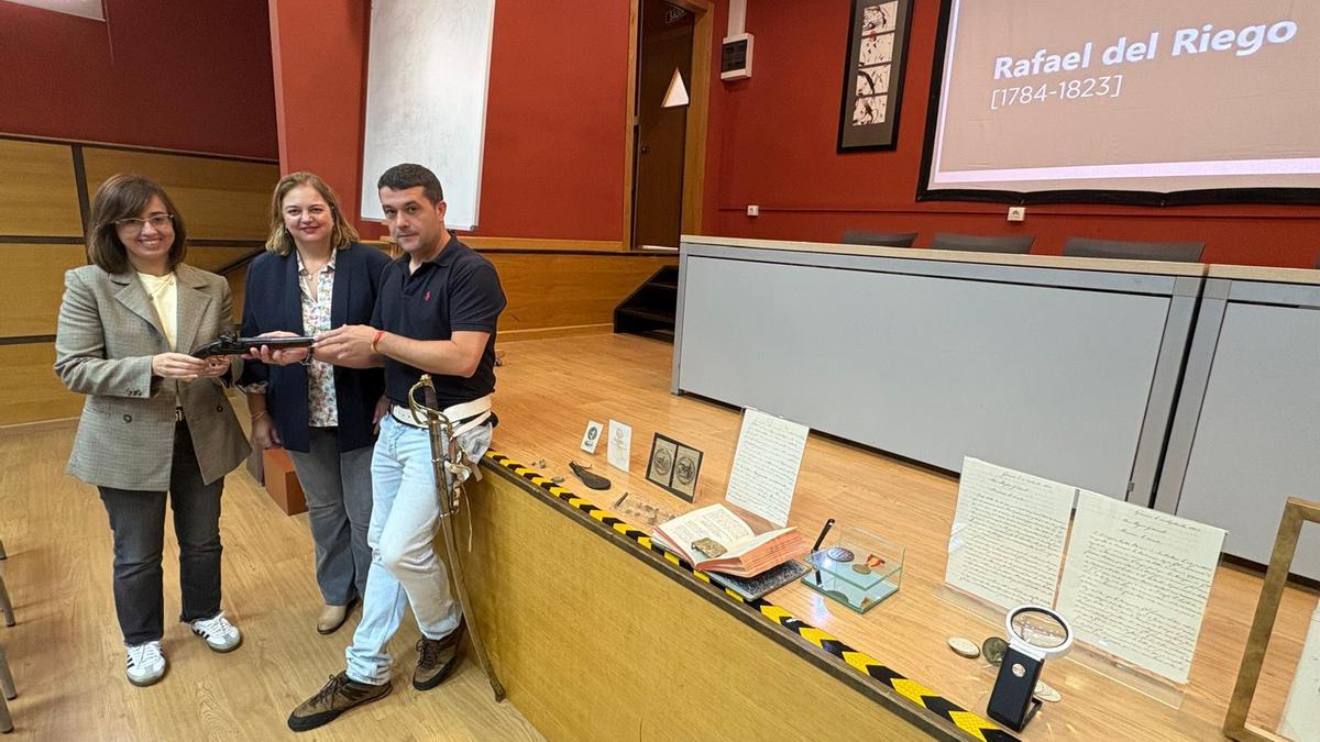 La edil Karina Peláez, la alcadesa Montse Fernández y Pedro Villanueva ante la exposición de objetos en el salón de actos del IES Concejo de Tineo.