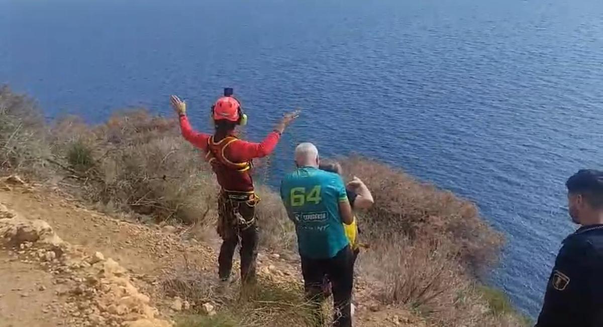 Un bombero del grupo de rescate hace indicaciones al helicóptero. Junto a él, la excursionista accidentada y su compañero