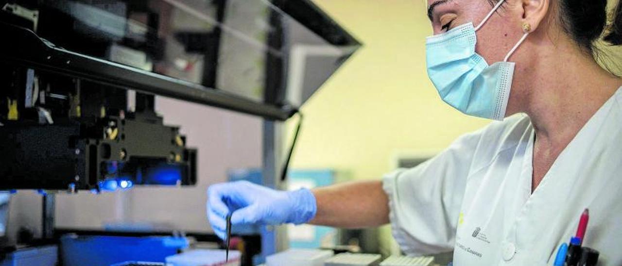 Una investigadora del Hospital Universitario de Canarias (HUC) deposita muestras sospechosas de coronavirus en una máquina para hacer PCR. | | ANDRÉS GUTIÉRREZ