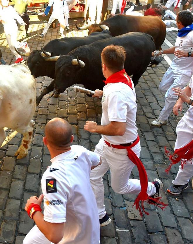 Los participantes corren junto a los toros Victoriano del Río Cortés en la tercera carrera de los San Fermines en Pamplona, norte de España.