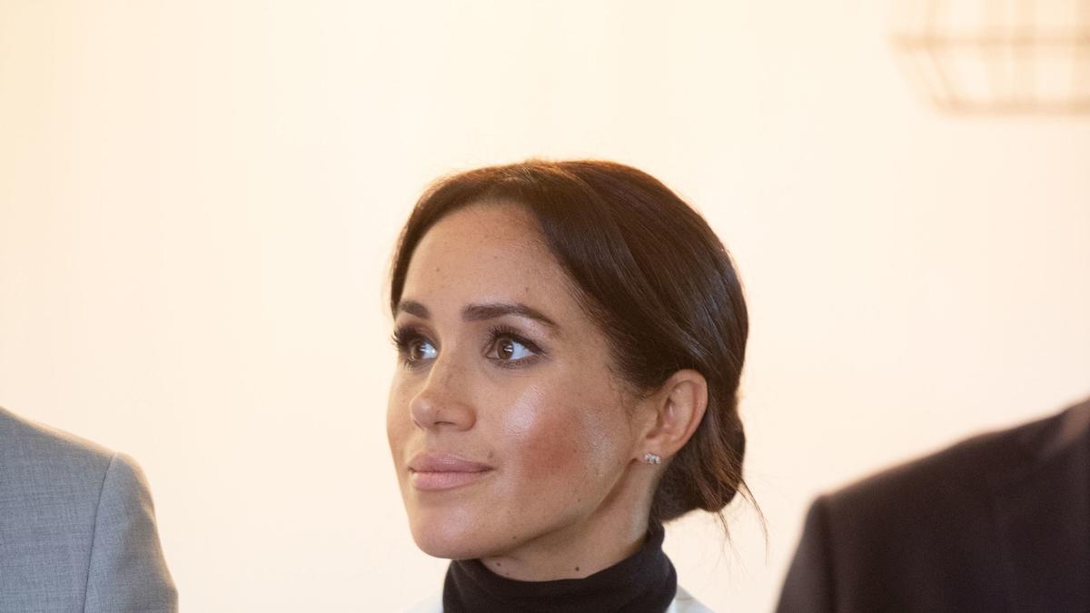 Meghan Markle con top negro y blazer blanca a rayas