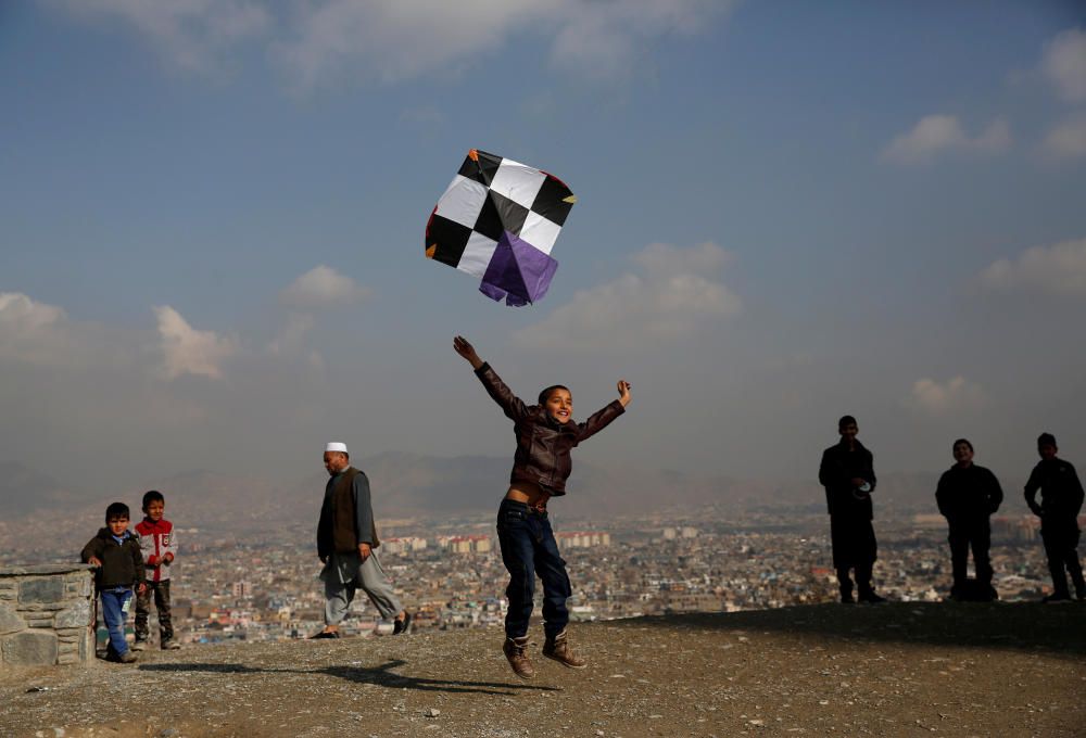 An Afghan boy launches a kite as he plays on top ...