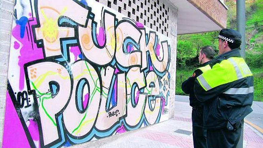 Dos agentes municipales, junto al polémico graffiti.