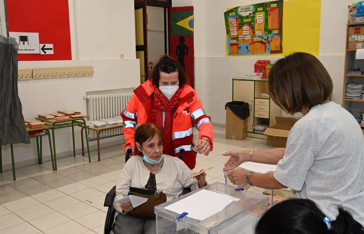 Cruz Roja ayuda a una mujer con movilidad reducida a votar en Badajoz.