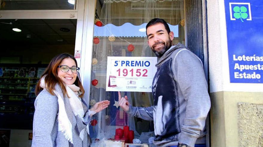 Los propietarios del estanco de Pinoso posan junto al cartel del quinto premio de la Lotería de Navidad vendido allí