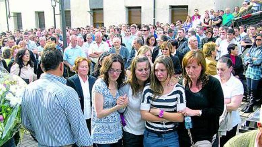 Arriba, el féretro del minero fallecido, Manuel López, a su llegada a la iglesia de Cerredo. A la izquierda, la esposa y la hija mayor de Manuel López (primera y segunda por la derecha), consoladas por amigos y familiares.