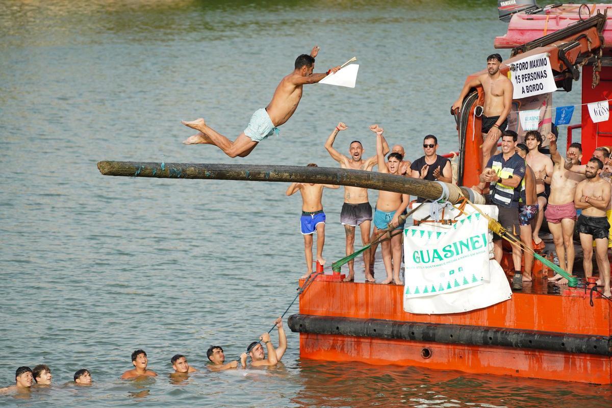 La 'cucaña', el juego centenario que regresa cada verano al río Guadalquivir por la Velá de Santa Ana en imágenes