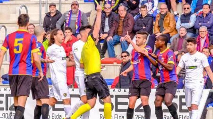 El colegiado del Eldense-Hércules amonesta a un jugador local, el pasado 12 de febrero.