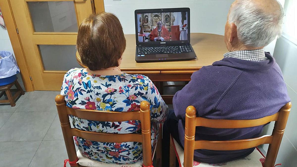 Dos personas mayores ven la misa de Alcañices en directo por internet. | Ch. S.