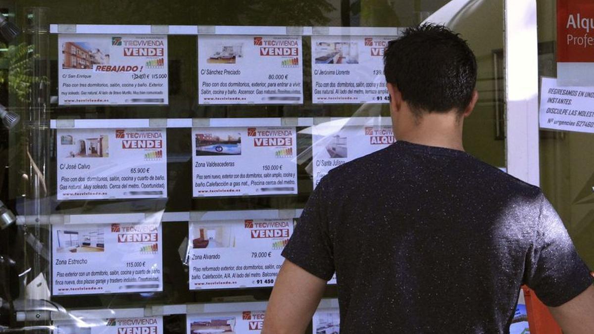 Un joven observa ofertas en una inmobiliaria.